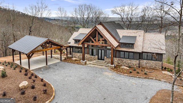 chalet / cabin featuring a carport, stone siding, and driveway