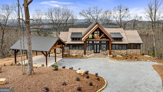 view of front of home with gravel driveway, french doors, and stone siding