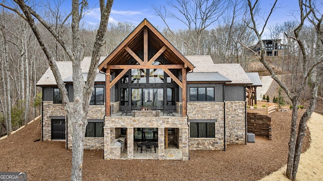 rear view of house with a patio, stone siding, and central AC