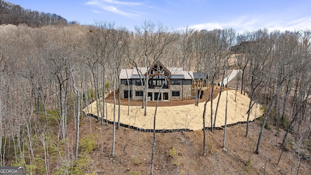 exterior space featuring stone siding and a wooded view