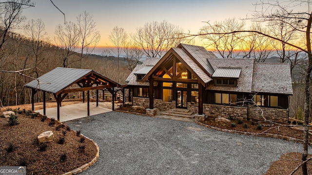 chalet / cabin featuring a carport, stone siding, and driveway