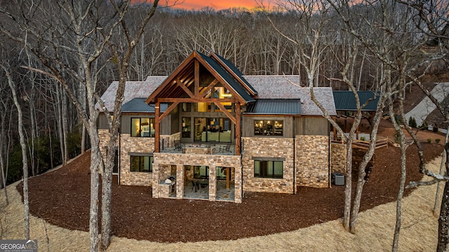 exterior space featuring a patio, a balcony, stone siding, and metal roof