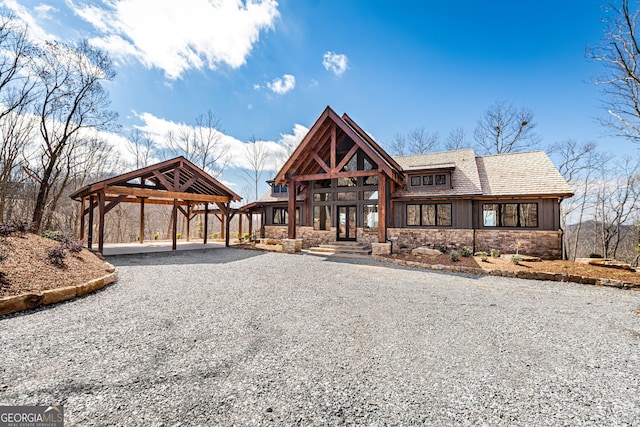 view of front of house with stone siding and gravel driveway