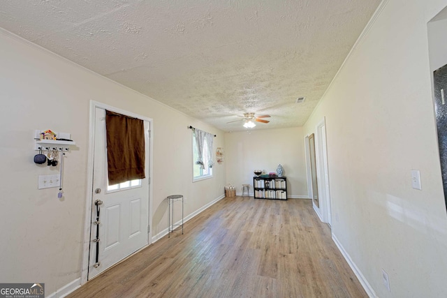 entryway with baseboards, a textured ceiling, ceiling fan, and light wood finished floors