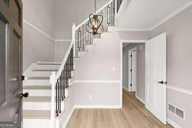 interior space featuring visible vents, crown molding, baseboards, stairway, and wood finished floors