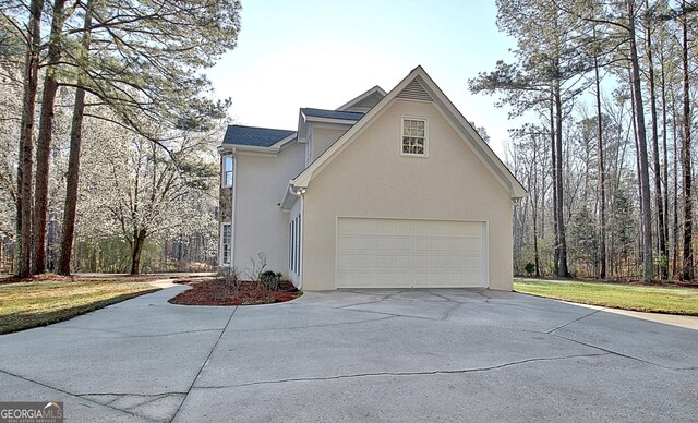 view of side of property with stucco siding, concrete driveway, and a garage