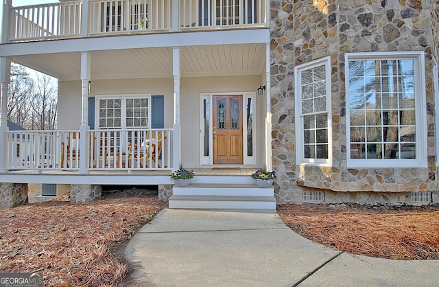 doorway to property with stone siding and covered porch