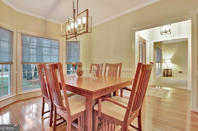 dining area with visible vents, an inviting chandelier, light wood-style flooring, and crown molding