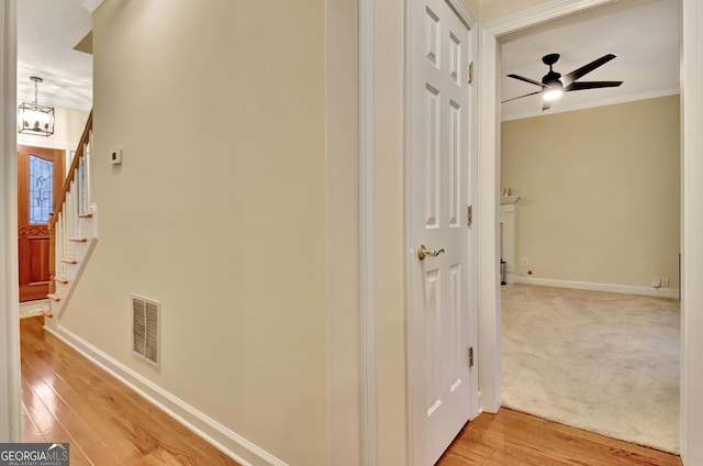 corridor featuring stairway, baseboards, visible vents, crown molding, and light wood-type flooring