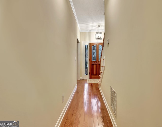 corridor with light wood-style floors, visible vents, baseboards, and a notable chandelier