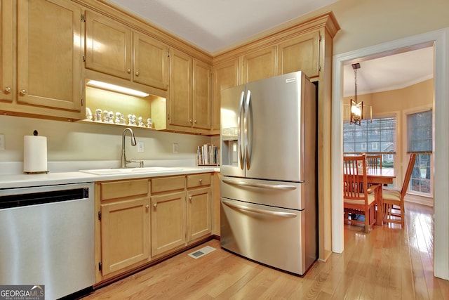 kitchen with a sink, stainless steel appliances, light wood-style floors, and light brown cabinets