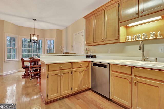 kitchen with a peninsula, light wood-style flooring, a sink, dishwasher, and a chandelier