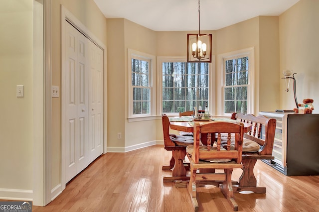 dining room with baseboards, an inviting chandelier, and light wood finished floors