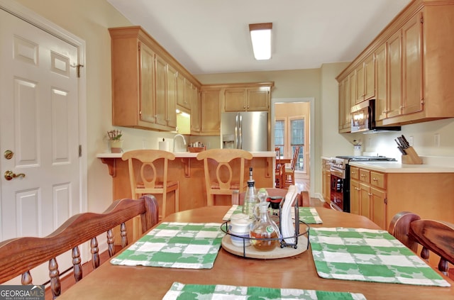 kitchen with a kitchen bar, appliances with stainless steel finishes, light countertops, and a peninsula