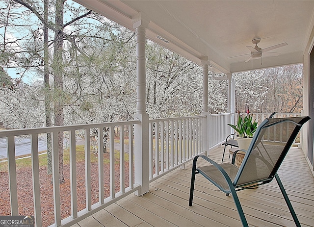 wooden deck featuring a porch, a ceiling fan, and visible vents