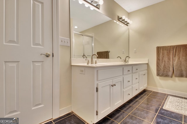 full bathroom featuring a sink, a shower stall, tile patterned flooring, double vanity, and baseboards