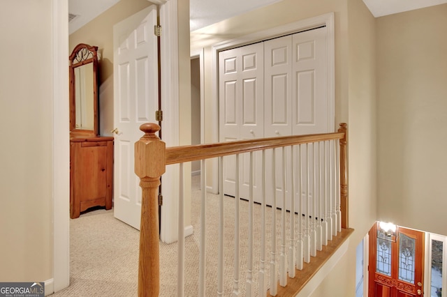 hallway with baseboards, an upstairs landing, visible vents, and carpet flooring