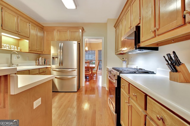 kitchen with light brown cabinetry, light countertops, appliances with stainless steel finishes, light wood-style floors, and a sink