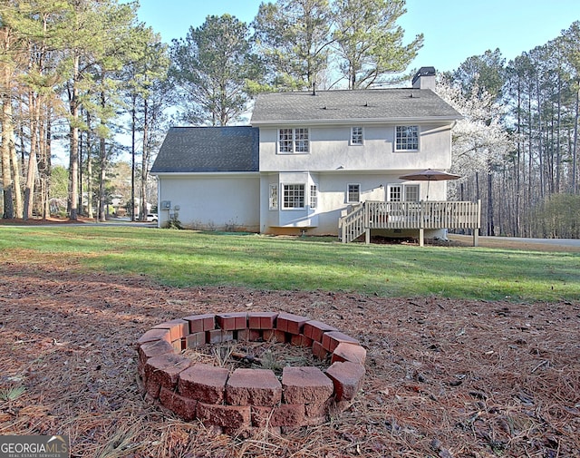 back of house featuring a deck, an outdoor fire pit, a lawn, and a chimney