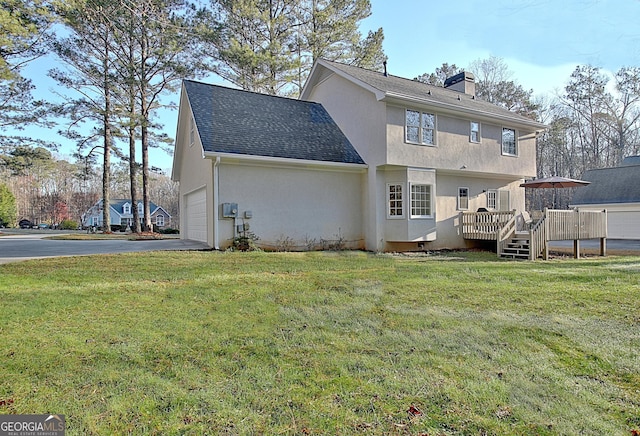 back of house featuring stucco siding, a yard, a chimney, and aphalt driveway