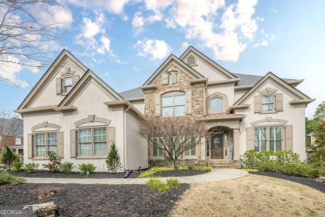 view of front of home featuring a shingled roof, stone siding, and stucco siding