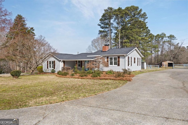 ranch-style house featuring a front lawn, driveway, and a chimney