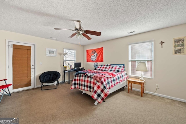 carpeted bedroom featuring visible vents, baseboards, a textured ceiling, and a ceiling fan