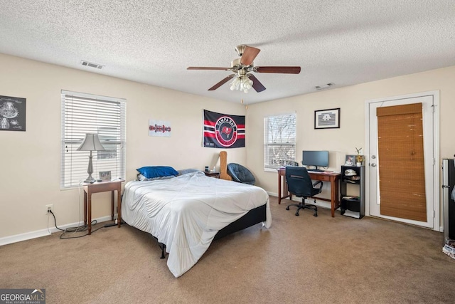 bedroom featuring a ceiling fan, visible vents, carpet floors, and a textured ceiling