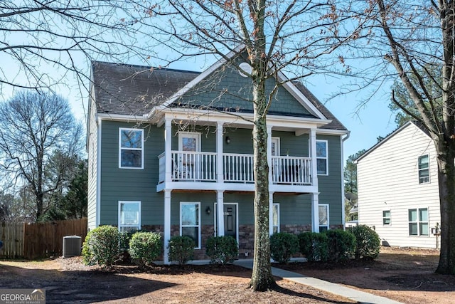 view of front of house with a balcony, roof with shingles, central AC, and fence