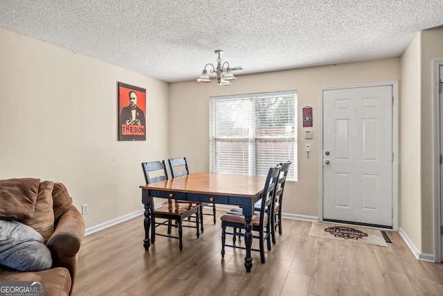 dining space with baseboards, a notable chandelier, wood finished floors, and a textured ceiling