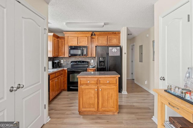 kitchen featuring a kitchen island, black appliances, light wood-style floors, a textured ceiling, and tasteful backsplash