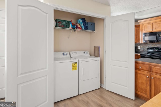 washroom with washer and dryer, laundry area, light wood-type flooring, and a textured ceiling