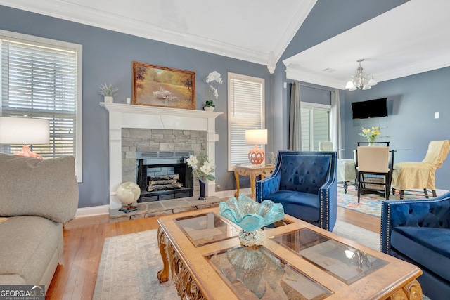 living area featuring a chandelier, vaulted ceiling, ornamental molding, a fireplace, and wood finished floors