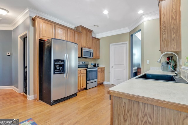 kitchen with appliances with stainless steel finishes, light wood-type flooring, crown molding, and a sink