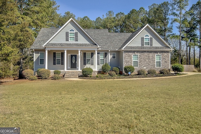 view of front of house featuring covered porch, a front yard, and a shingled roof