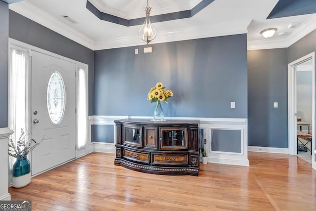 entrance foyer featuring a tray ceiling, visible vents, wood-type flooring, and ornamental molding