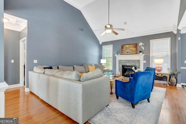 living area with light wood finished floors, crown molding, baseboards, ceiling fan, and a fireplace