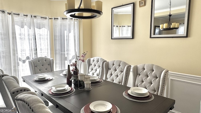 dining space with a decorative wall, wainscoting, and crown molding