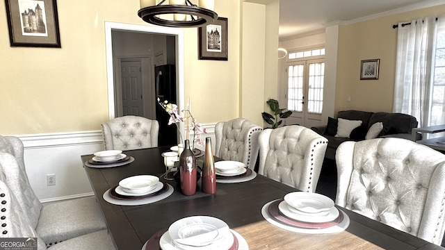 dining space with french doors and crown molding