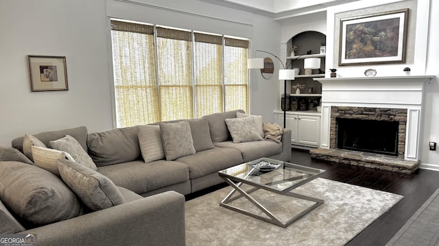 living room featuring built in shelves, a fireplace, and dark wood-style flooring