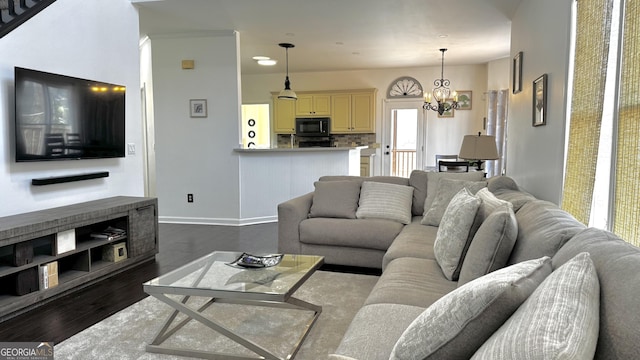 living room featuring dark wood finished floors, a notable chandelier, and baseboards