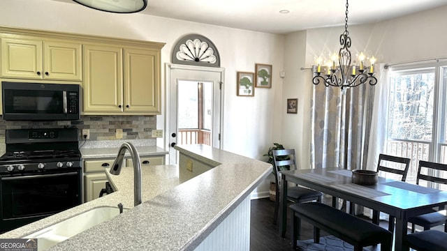 kitchen featuring a notable chandelier, black appliances, cream cabinetry, a sink, and tasteful backsplash