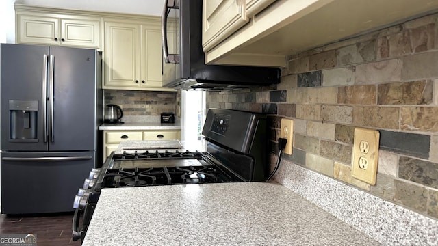 kitchen with dark wood finished floors, light countertops, decorative backsplash, cream cabinetry, and black appliances