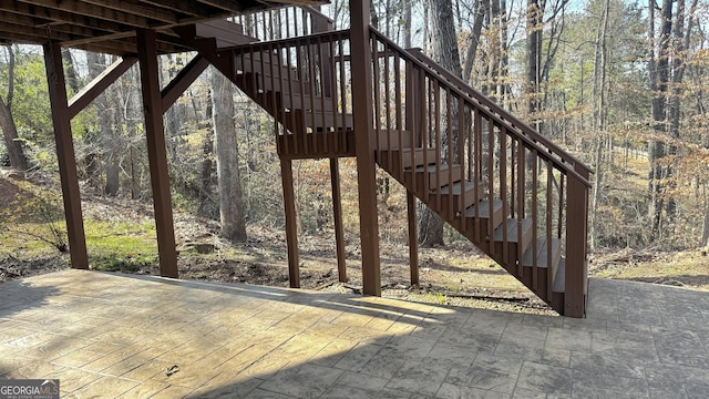 wooden deck featuring a patio area, stairway, and a view of trees