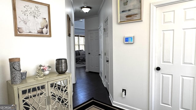 hallway featuring dark wood finished floors, baseboards, and ornamental molding