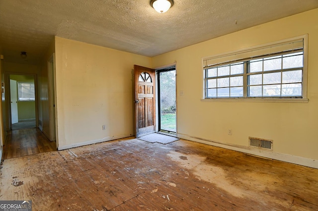 spare room with baseboards, visible vents, and a textured ceiling