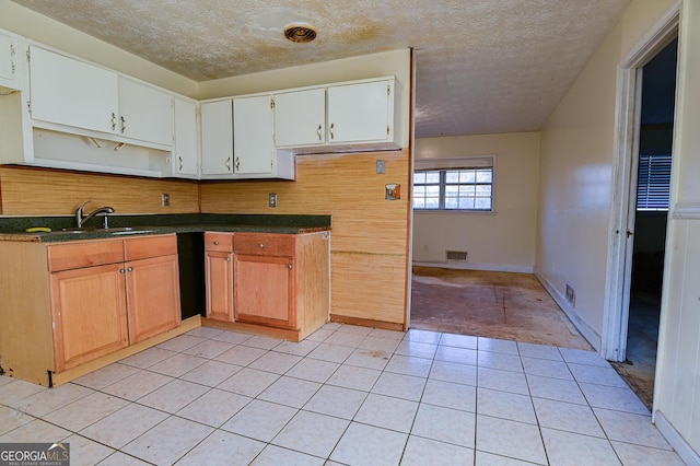 kitchen featuring visible vents, light tile patterned flooring, a sink, a textured ceiling, and dark countertops