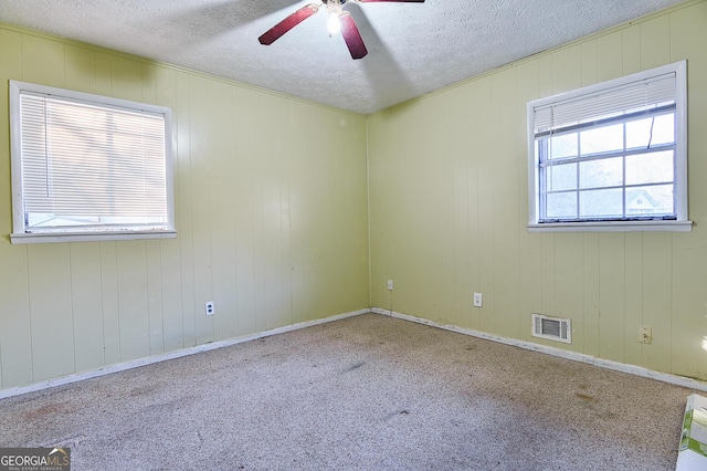 carpeted empty room featuring visible vents, a textured ceiling, and a ceiling fan