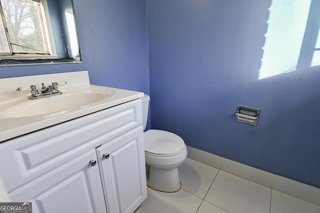 half bath featuring tile patterned flooring, toilet, vanity, and baseboards