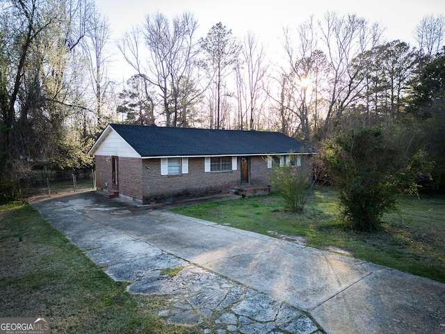 ranch-style home featuring brick siding, concrete driveway, and a front yard